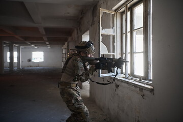 Image showing soldier in action near window changing magazine and take cover