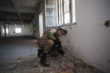 Image showing soldier in action near window changing magazine and take cover