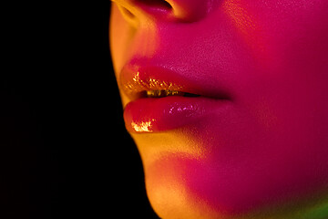 Image showing Close up portrait of female fashion model in neon light on dark studio background.