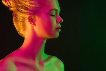 Image showing Portrait of female fashion model in neon light on dark studio background.