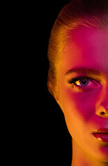 Image showing Portrait of female fashion model in neon light on dark studio background.