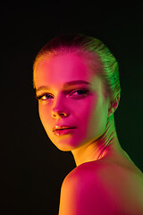 Image showing Portrait of female fashion model in neon light on dark studio background.