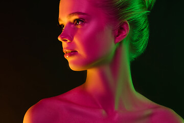 Image showing Portrait of female fashion model in neon light on dark studio background.