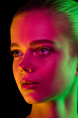 Image showing Portrait of female fashion model in neon light on dark studio background.