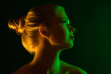 Image showing Portrait of female fashion model in neon light on dark studio background.