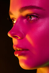 Image showing Portrait of female fashion model in neon light on dark studio background.