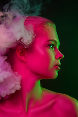 Image showing Portrait of female fashion model in neon light on dark studio background.