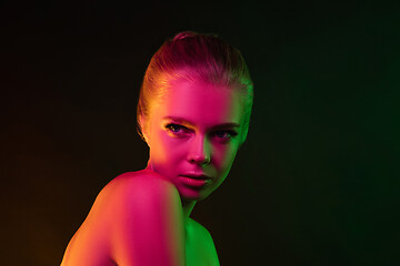 Image showing Portrait of female fashion model in neon light on dark studio background.