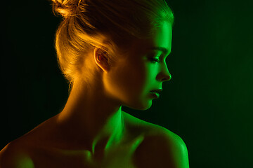 Image showing Portrait of female fashion model in neon light on dark studio background.