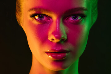 Image showing Portrait of female fashion model in neon light on dark studio background.