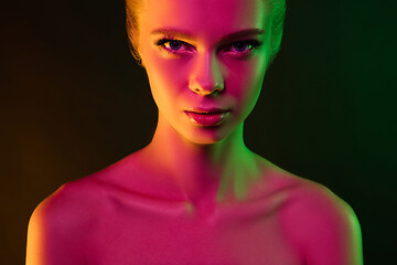 Image showing Portrait of female fashion model in neon light on dark studio background.