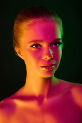 Image showing Portrait of female fashion model in neon light on dark studio background.