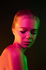 Image showing Portrait of female fashion model in neon light on dark studio background.