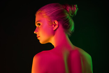 Image showing Portrait of female fashion model in neon light on dark studio background.