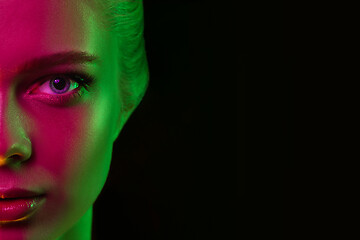 Image showing Portrait of female fashion model in neon light on dark studio background.