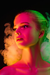 Image showing Portrait of female fashion model in neon light on dark studio background.