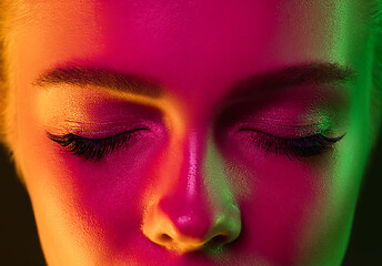 Image showing Close up portrait of female fashion model in neon light on dark studio background.