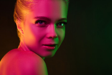 Image showing Portrait of female fashion model in neon light on dark studio background.