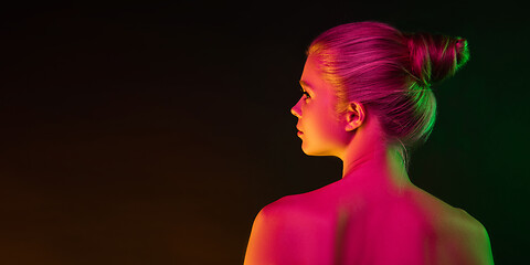 Image showing Portrait of female fashion model in neon light on dark studio background.