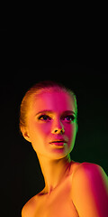 Image showing Portrait of female fashion model in neon light on dark studio background.