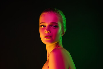 Image showing Portrait of female fashion model in neon light on dark studio background.