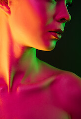 Image showing Portrait of female fashion model in neon light on dark studio background.