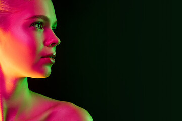 Image showing Portrait of female fashion model in neon light on dark studio background.