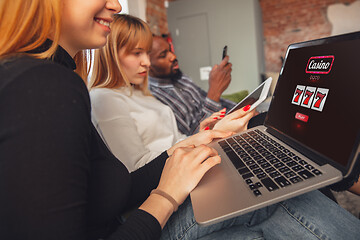 Image showing Friends using laptop with mobile app for online casino, cheering people look excited