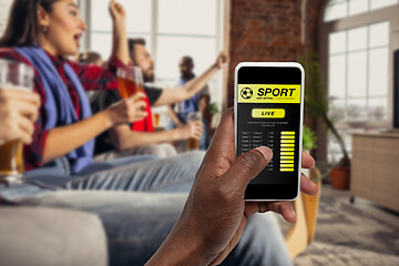 Image showing Device screen with mobile app for betting and score, cheering friends, fans on background