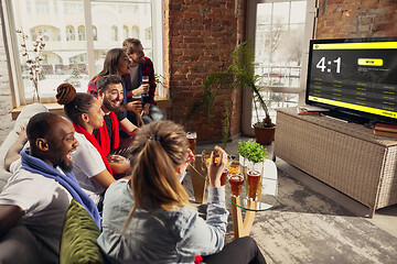 Image showing TV screen with mobile app for betting and score, cheering friends, fans in front of it look excited