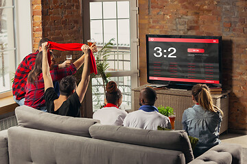 Image showing TV screen with mobile app for betting and score, cheering friends, fans in front of it look excited