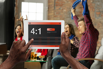 Image showing Device screen with mobile app for betting and score, cheering friends, fans on background