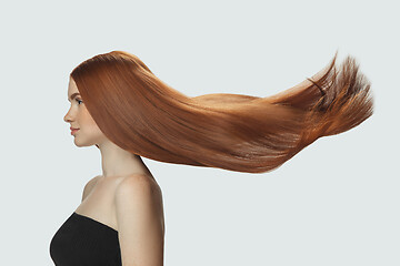 Image showing Beautiful model with long smooth, flying red hair isolated on white studio background.