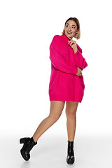 Image showing Beautiful young woman in bright pink comfortable sweater, long sleeve isolated on white studio background