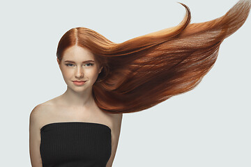 Image showing Beautiful model with long smooth, flying red hair isolated on white studio background.