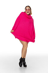 Image showing Beautiful young woman in bright pink comfortable sweater, long sleeve isolated on white studio background