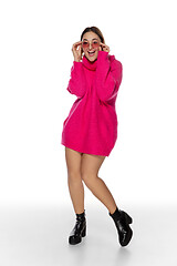 Image showing Beautiful young woman in bright pink comfortable sweater, long sleeve isolated on white studio background