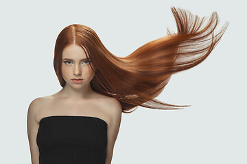 Image showing Beautiful model with long smooth, flying red hair isolated on white studio background.