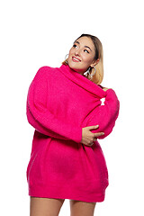 Image showing Beautiful young woman in bright pink comfortable sweater, long sleeve isolated on white studio background