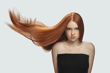 Image showing Beautiful model with long smooth, flying red hair isolated on white studio background.