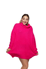 Image showing Beautiful young woman in bright pink comfortable sweater, long sleeve isolated on white studio background