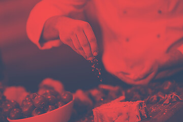 Image showing Chef putting salt on juicy slice of raw steak