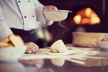 Image showing chef sprinkling flour over fresh pizza dough