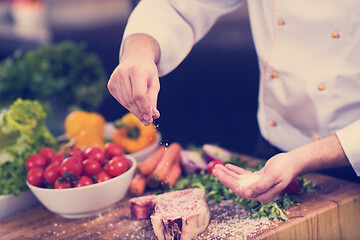 Image showing Chef putting salt on juicy slice of raw steak