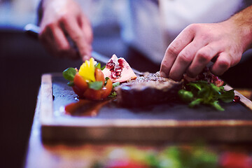 Image showing closeup of Chef hands serving beef steak