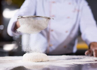 Image showing chef sprinkling flour over fresh pizza dough