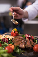 Image showing Chef hand finishing steak meat plate