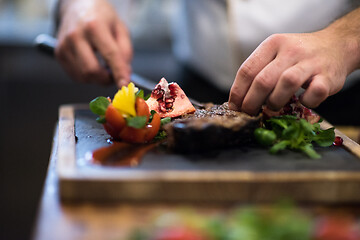 Image showing closeup of Chef hands serving beef steak