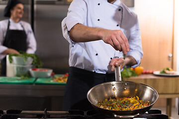 Image showing chef putting spices on vegetables in wok