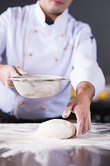 Image showing chef sprinkling flour over fresh pizza dough